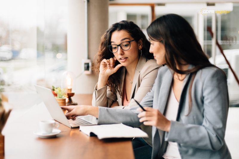 Two businesswomen discussing GDPR compliance on a laptop, analyzing Google Recaptcha cookies and their impact on user privacy.